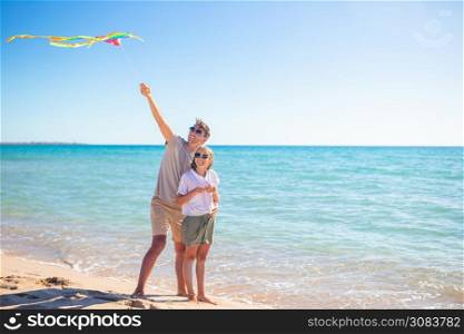 Father with daughter in summer playing with kite on the beach. Family playing with a kite on the beach