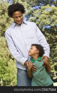 Father with hands on son&acute;s shoulders as boy looks up at him.