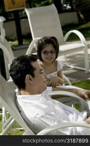 Father with his daughter sitting on armchairs and reading