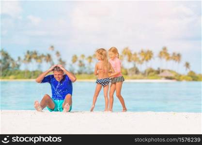 Father with kids on the beach enjoying beach vacation, splashing and having fun together. Happy beautiful family on a tropical beach vacation