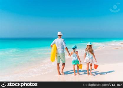 Father with kids on the beach going to swim. Family vacation. Happy beautiful family on a tropical beach vacation