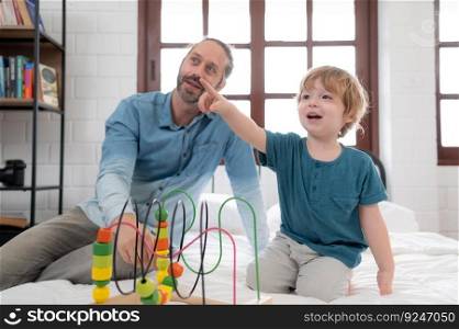 Father with little boy have fun playing with your new toys in the bedroom together. Toys that enhance children&rsquo;s thinking skills.