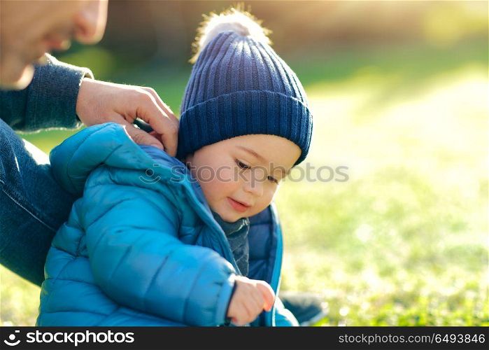 Father with little son playing outdoors in sunny spring day, having fun together on the fresh green grass field in the park, happy family life. Father with little son playing outdoors