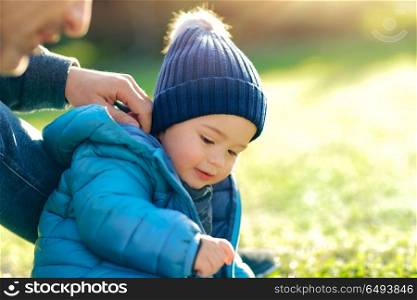 Father with little son playing outdoors in sunny spring day, having fun together on the fresh green grass field in the park, happy family life. Father with little son playing outdoors