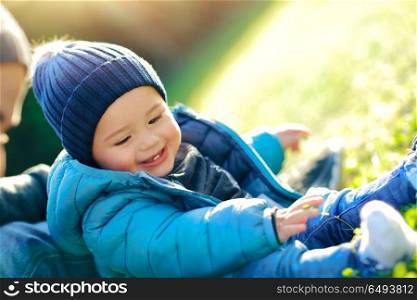 Father with little son playing outdoors on sunny spring day, having fun together on the fresh green grass field in the park, happy family life. Father with little son playing outdoors