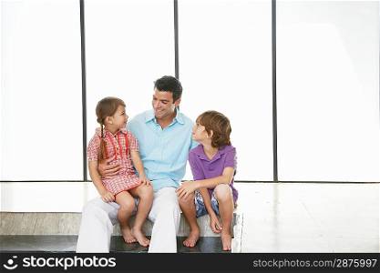 Father with son (7-9) and daughter (5-6) sitting indoors