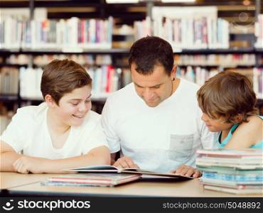 Father with sons in library with books. Father with sons in library