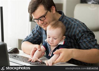 Father working at home with his little baby boy