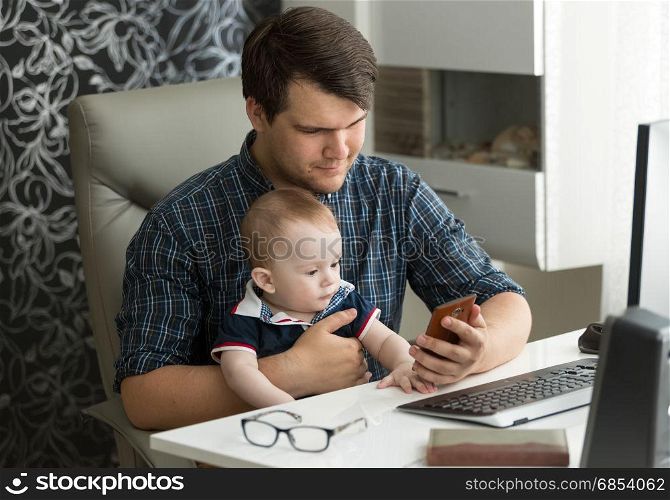 Father working from home and taking care of his baby son