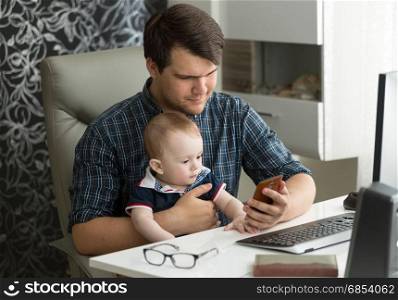 Father working from home and taking care of his baby son