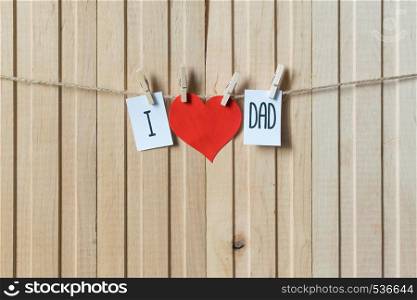 Fathers day concept. Message with red paper heart hanging with pins over light wooden board.. Fathers day concept. Message with paper heart hanging with pins over light wooden board.