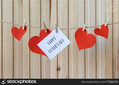 Fathers day message with paper hearts hanging with clothespins over light wooden board.. Fathers day concept. Message with paper hearts hanging with clothespins over light wooden board.