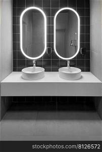Faucets with washbasin in public restroom in grey colors