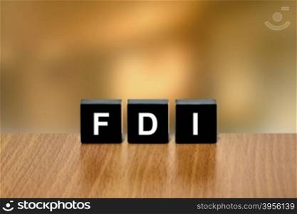 FDI or Foreign direct investment on black block with blurred background