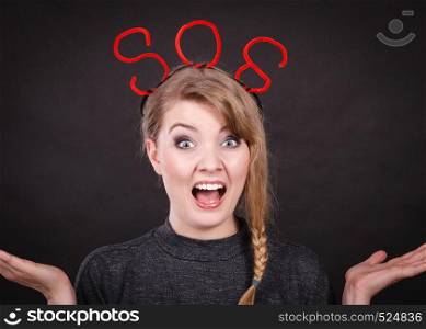 Fear and fright. Young blonde terrified woman needs help. Frightened hopeless female with red sos sign symbol on dark background.. Frightened woman with sos help sign.
