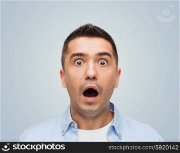 fear, emotions, horror and people concept - scared man with big eyes and open mouth shouting over gray background