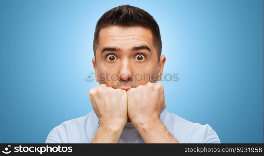fear, horror, emotions and people concept - scared man face over blue background
