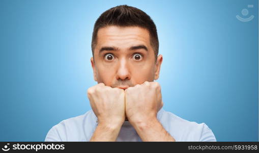 fear, horror, emotions and people concept - scared man face over blue background