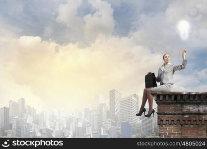 Fearless businesswoman with suitcase sitting on building top. Taking break from office