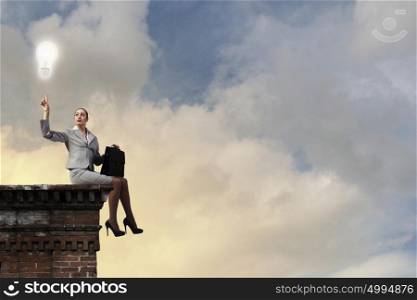 Fearless businesswoman with suitcase sitting on building top. Taking break from office