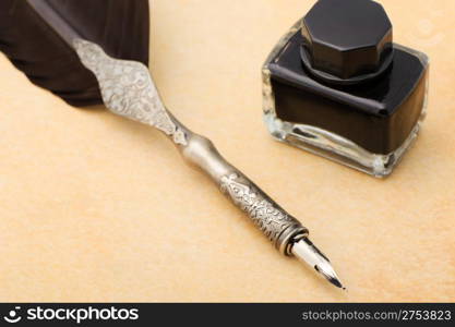 Feather quill and inkwell on an old paper. Photo closeup