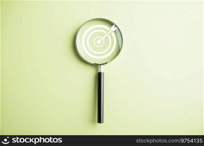 Features a target board captured inside a magnifier glass, illustrating the focus on business objectives, target search concept, and attaining success. Isolated on a background with copy space.. Target board inside magnifier glass for focus business objective