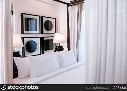 FEB 10, 2014 Chiang Mai, THAILAND - Asian contemporary hotel bedroom with wooden four poster bed with curtain, white sheet, pillows, lamps and modern wall picture frames