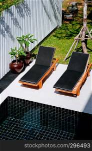 FEB 10, 2014 Chiang Mai, THAILAND - Outdoor hotel furniture black modern sunbeds by the dark blue pool and tropical garden, top view