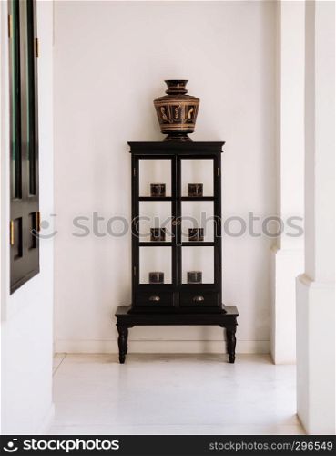 FEB 10, 2014 Chiang Mai, THAILAND - Vintage wooden showcase with northern Thai style black coloured antique lacquerware vase and boxes at white balcony