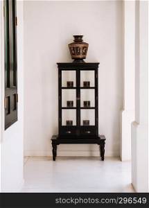 FEB 10, 2014 Chiang Mai, THAILAND - Vintage wooden showcase with northern Thai style black coloured antique lacquerware vase and boxes at white balcony