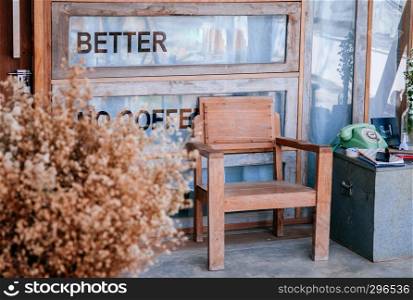 FEB 11, 2014 Chiang Mai, THAILAND - Home cafe decoration vintage wooden armchair furniture, glass window wall, galvanized steel box, vintage telephone and and dried flower vase in foreground.
