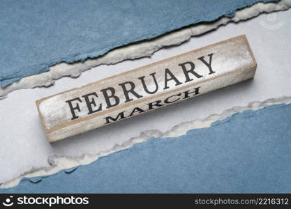 February text on grunge wooden block against handmade rag paper in blue tones, calendar concept