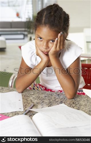 Fed Up Girl Doing Homework In Kitchen