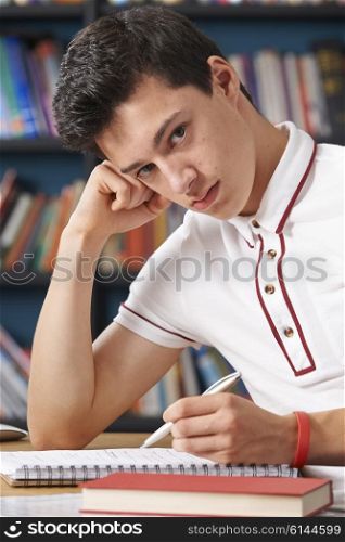 Fed Up Male Teenage Student Working In Library