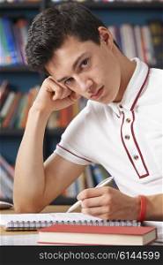 Fed Up Male Teenage Student Working In Library