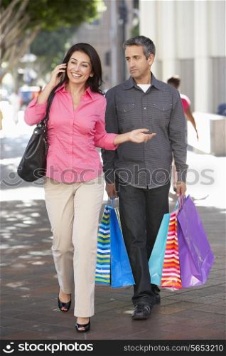 Fed Up Man Carrying Partners Shopping Bags On City Street