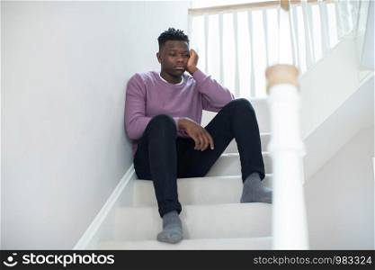 Fed Up Teenage Boy Sitting On Stairs At Home