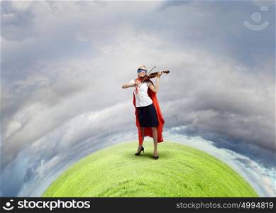 Feel yourself a hero!. Young woman in super hero costume playing violin