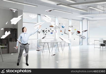 Feeling free and careless. Young businessman in modern office interior playing with paper plane