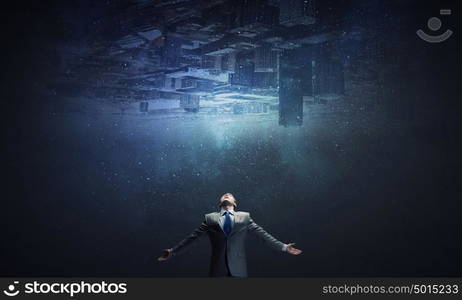 Feeling his power. Businessman with hands spread apart and city reflection in sky