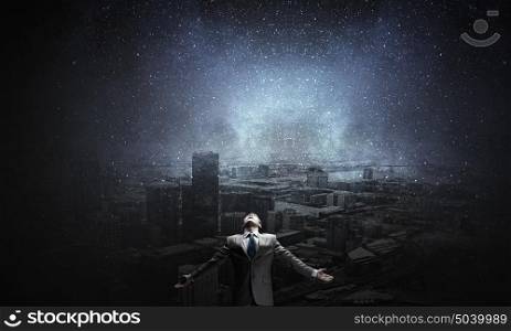Feeling his power. Businessman with hands spread apart on city landscape background