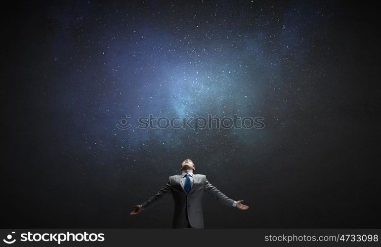 Feeling his power. Businessman with hands spread apart on dark background