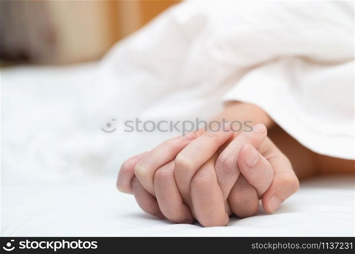 Feeling on hands of passion couple having sex. two Lovers couple Holding hands under blanket white sheets on the bed with lust and making love. concept having sexual romantic moments.