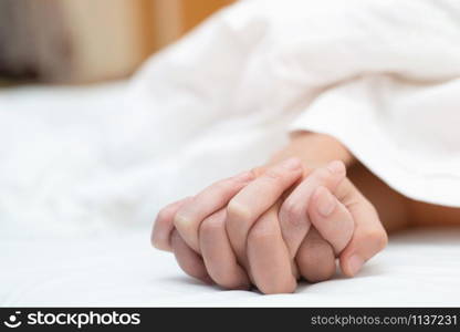 Feeling on hands of passion couple having sex. two Lovers couple Holding hands under blanket white sheets on the bed with lust and making love. concept having sexual romantic moments.