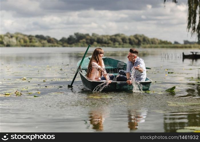 Feeling playful. Beautiful young couple enjoying romantic date while rowing a boat. Feeling playful. Beautiful young couple enjoying romantic date while rowing a boat. Happy to have each other.