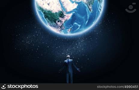 Feeling powerful. Young businessman and Earth planet above. Elements of this image are furnished by NASA