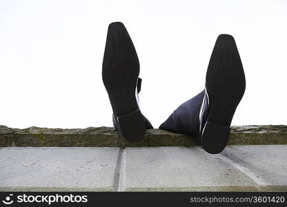 Feet dangling over wall, low angle view