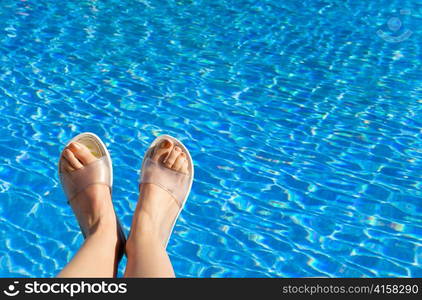 Feet in beach slippers on the brink of pool