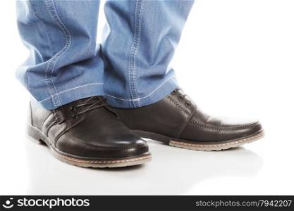 Feet in blue jeans and shoes with laces on a white background.