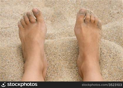 feet in the sand of the beach
